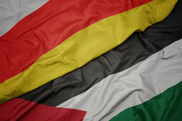Acenando bandeira colorida da Palestina e bandeira nacional da ossétia do sul . — Fotografia de Stock