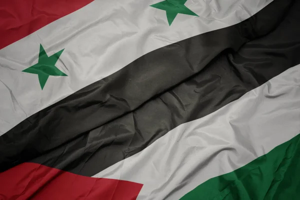 Zwaaiende kleurrijke vlag van Palestina en de nationale vlag van Syrië. — Stockfoto