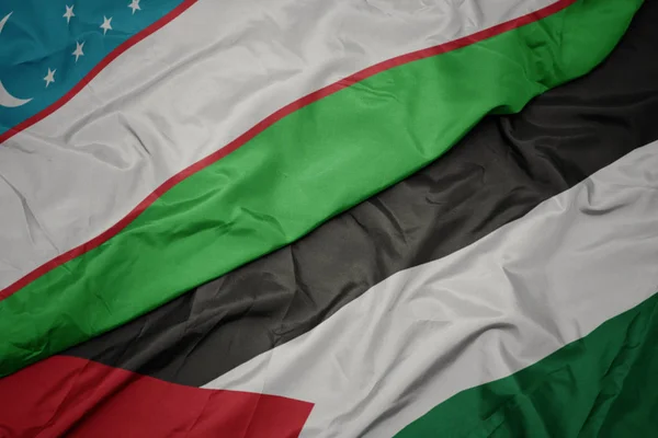 waving colorful flag of palestine and national flag of uzbekistan.