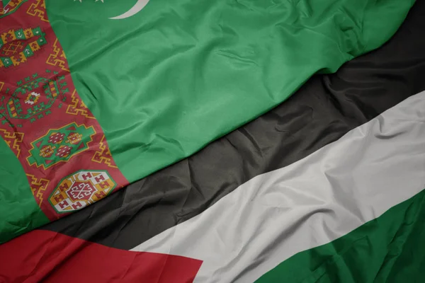 waving colorful flag of palestine and national flag of turkmenistan.