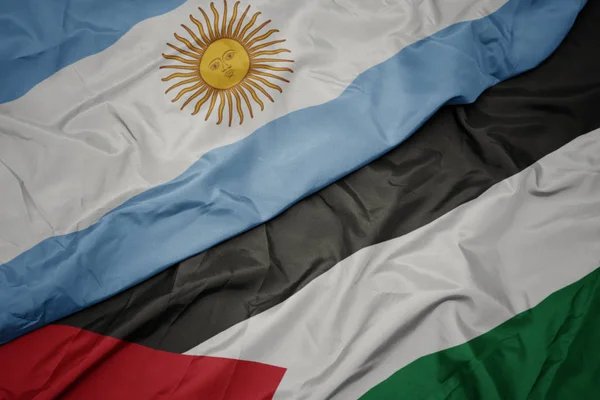 waving colorful flag of palestine and national flag of argentina.
