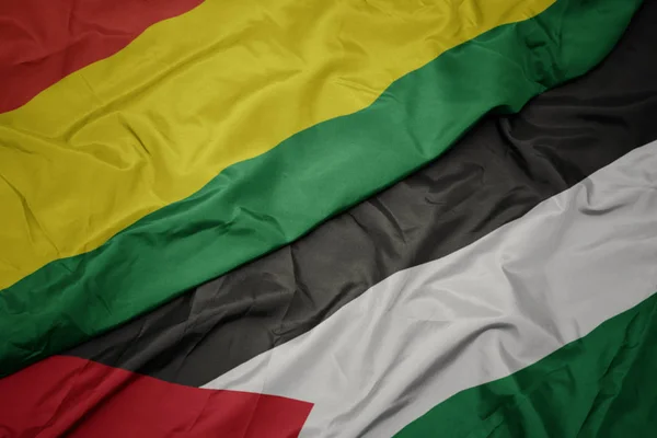 waving colorful flag of palestine and national flag of bolivia.