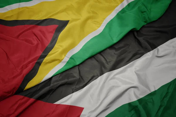 Waving colorful flag of palestine and national flag of guyana. — Stock Photo, Image