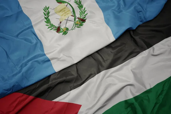 waving colorful flag of palestine and national flag of guatemala.