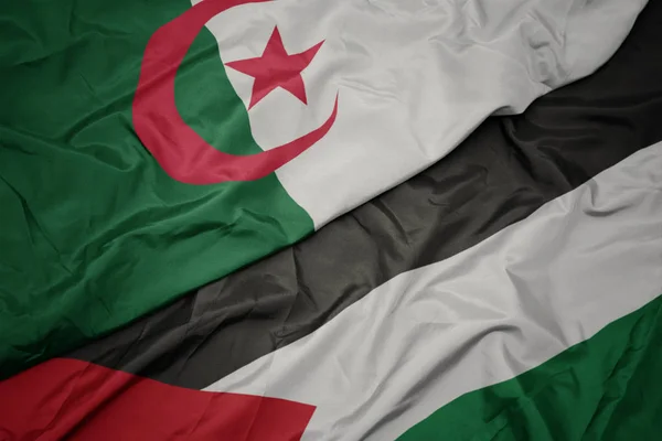 waving colorful flag of palestine and national flag of algeria.