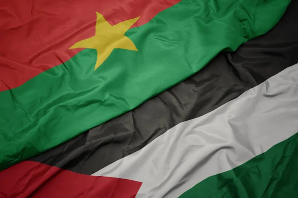 Ondeando colorida bandera de Palestina y bandera nacional de Burkina faso . — Foto de Stock