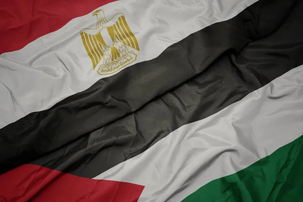 waving colorful flag of palestine and national flag of egypt .