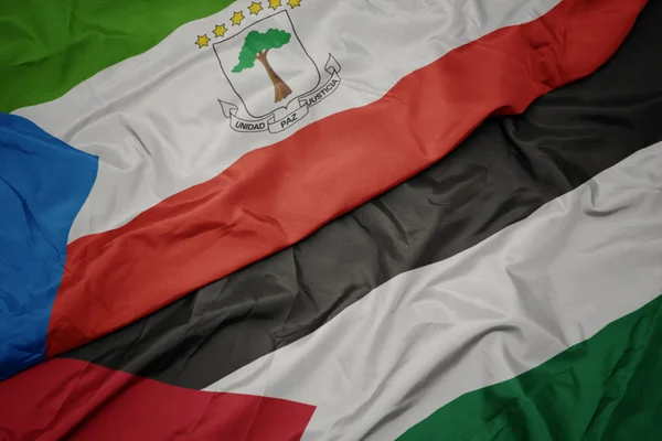 waving colorful flag of palestine and national flag of equatorial guinea.