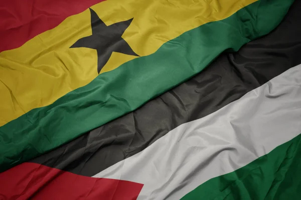 waving colorful flag of palestine and national flag of ghana.