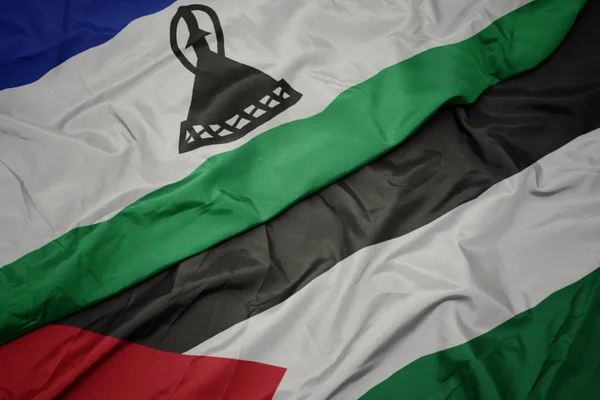 waving colorful flag of palestine and national flag of lesotho.
