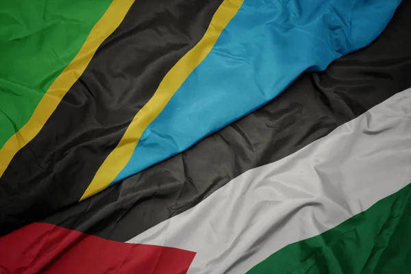 waving colorful flag of palestine and national flag of tanzania.