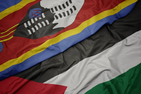 waving colorful flag of palestine and national flag of swaziland.