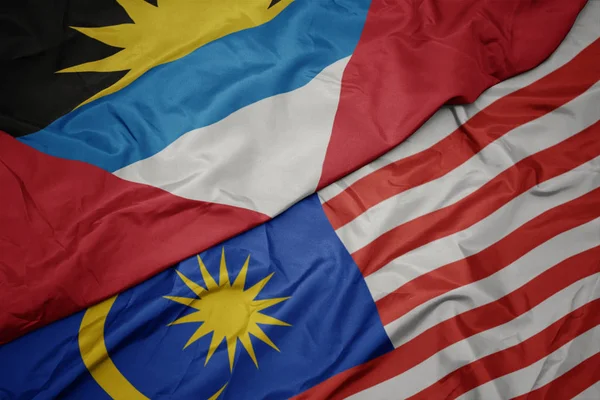 Sventolando bandiera colorata di malesia e bandiera nazionale di antigua e barbuda . — Foto Stock