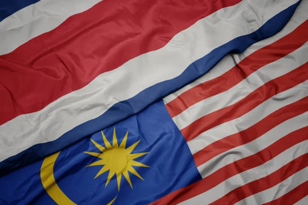 Zwaaiende kleurrijke vlag van Maleisië en de nationale vlag van Costa Rica. — Stockfoto