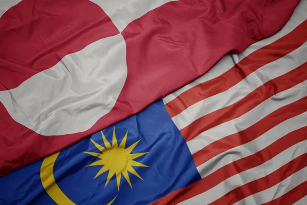 Waving colorful flag of malaysia and national flag of greenland. — Stock Photo, Image