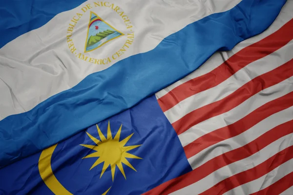 Sventolando bandiera colorata della Malesia e bandiera nazionale del Nicaragua . — Foto Stock