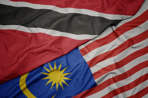 Sventolando bandiera colorata di malesia e bandiera nazionale di trinidad e tobago . — Foto Stock