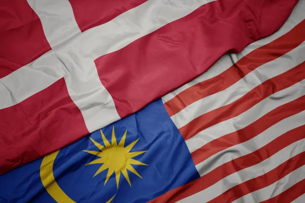Falujące kolorowe flagi Malezji i flagi narodowej Danii. — Zdjęcie stockowe