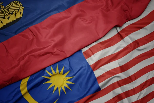 挥舞着五颜六色的马来西亚国旗和列支敦士登国旗. — 图库照片