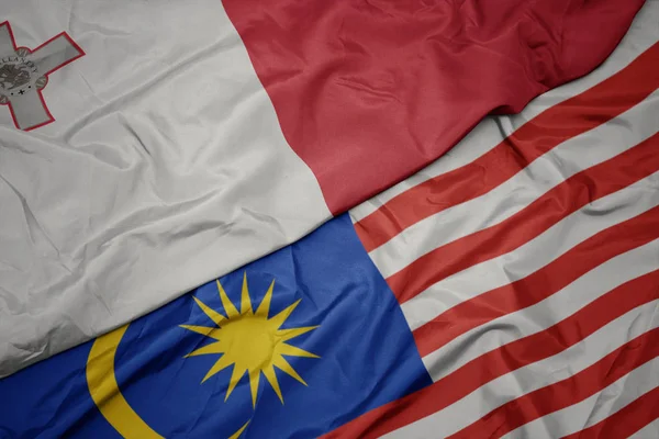 Sventolando bandiera colorata di malesia e bandiera nazionale di malta — Foto Stock
