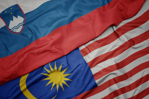 Размахивая красочным флагом Малайзии и национальным флагом Словении . — стоковое фото