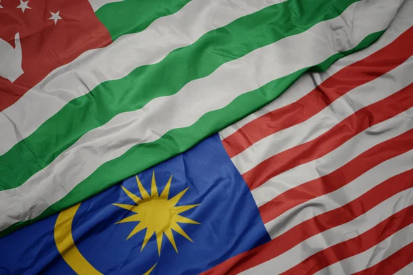 Schwenken bunte Flagge von Malaysia und Nationalflagge von Abchasien. — Stockfoto