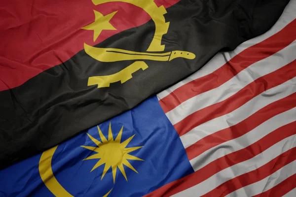 Waving colorful flag of malaysia and national flag of angola. — Stock Photo, Image