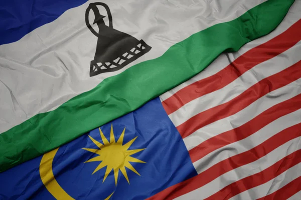 Schwenken bunte Flagge von Malaysia und Nationalflagge von Lesotho. — Stockfoto