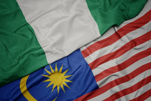 Sventolando bandiera colorata della Malesia e bandiera nazionale della Nigeria . — Foto Stock