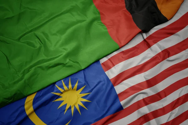 Sventolando bandiera colorata della Malesia e bandiera nazionale della zambia . — Foto Stock
