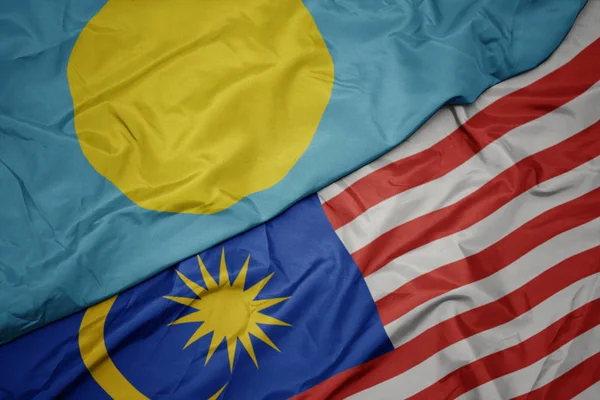 Размахивая красочным флагом Малайзии и национальным флагом Палау  . — стоковое фото