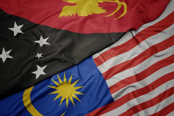 Schwenken bunte malaysische Flagge und Nationalflagge von Papua Neuguinea . — Stockfoto