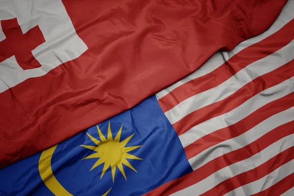 Schwenken bunte Flagge von Malaysia und Nationalflagge von Tonga . — Stockfoto