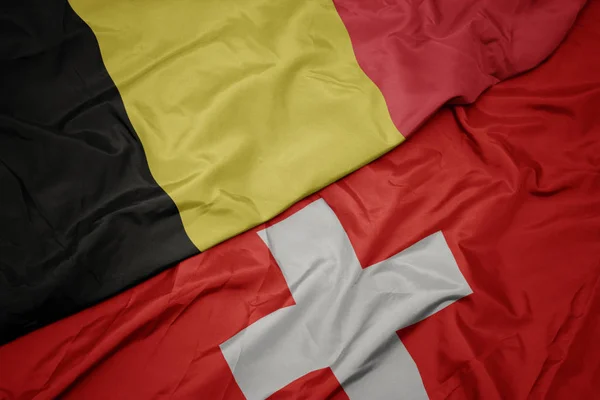 Acenando bandeira colorida da Suíça e bandeira nacional da Bélgica . — Fotografia de Stock