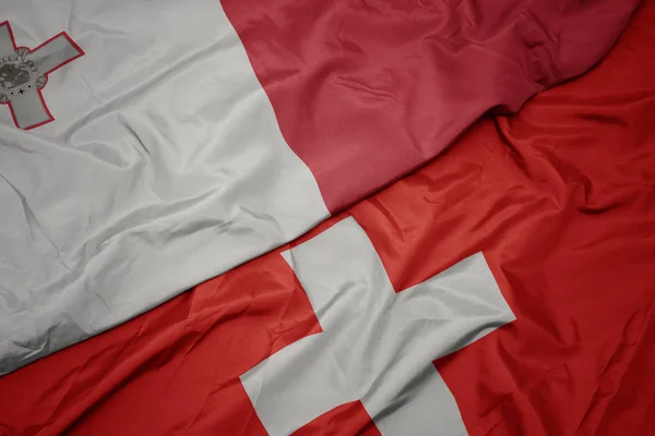 Размахивая красочным флагом Швейцарии и национального флага Мальты . — стоковое фото