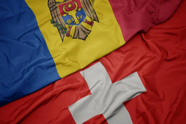 Ondeando colorida bandera de Suiza y bandera nacional de Moldavia . —  Fotos de Stock