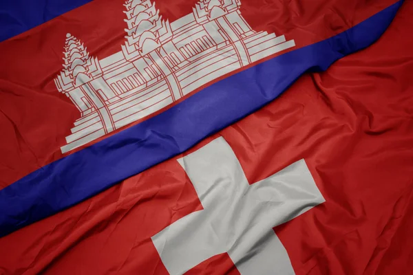 Schwenken bunte Flagge der Schweiz und Nationalflagge Kambodschas. — Stockfoto