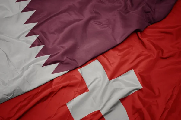 Schwenkt die bunte Flagge der Schweiz und die Nationalflagge Katars. — Stockfoto