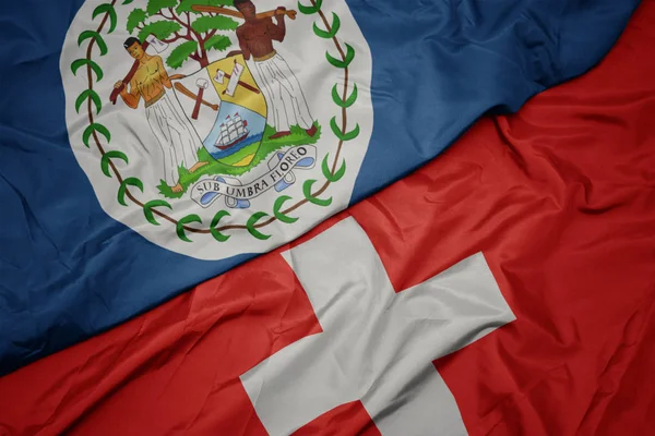 スイスのカラフルな旗とベリーズの国旗を振る. — ストック写真