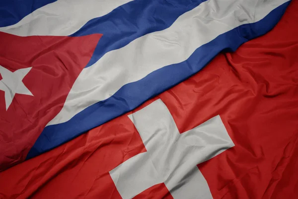 Agitant drapeau coloré de la Suisse et drapeau national de cuba . — Photo