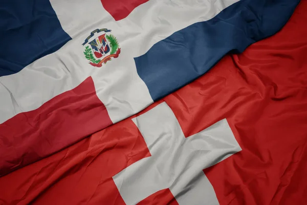 Ondeando colorida bandera de Suiza y bandera nacional de la República Dominicana . — Foto de Stock