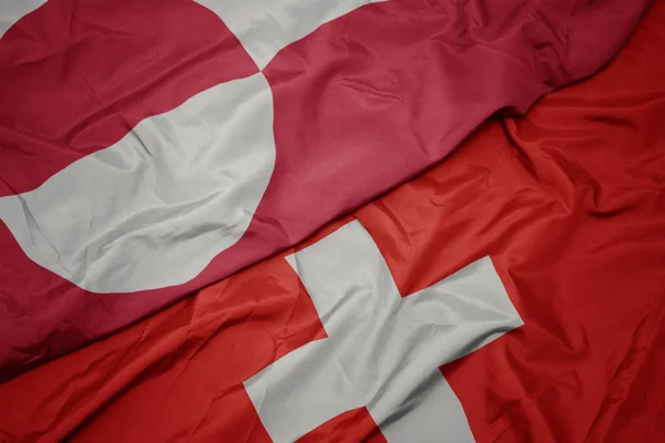 Falujące kolorowe flagi Szwajcarii i flagi narodowej Grenlandii. — Zdjęcie stockowe