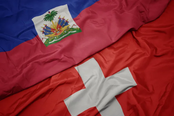 Agitant le drapeau coloré de la Suisse et le drapeau national de haiti . — Photo