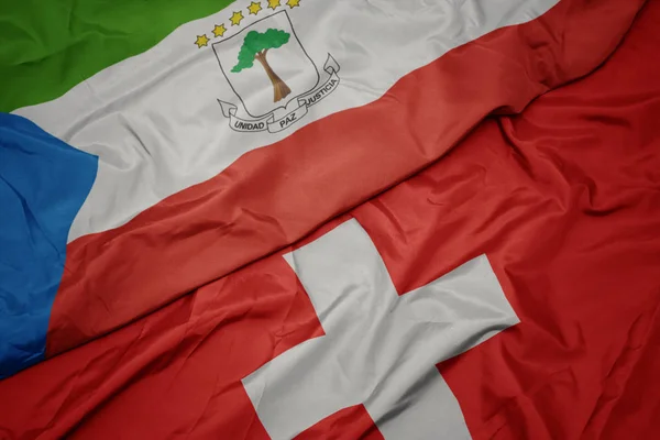 Sventolando bandiera colorata della Svizzera e bandiera nazionale della Guinea equatoriale . — Foto Stock