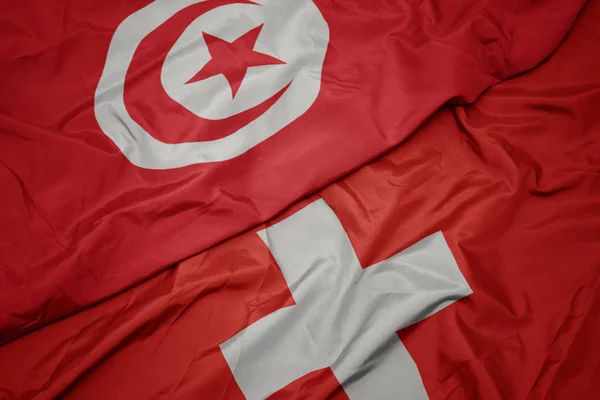 Waving colorful flag of switzerland and national flag of tunisia. — Stock Photo, Image
