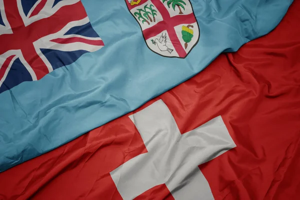 Waving colorful flag of switzerland and national flag of Fiji . — Stock Photo, Image