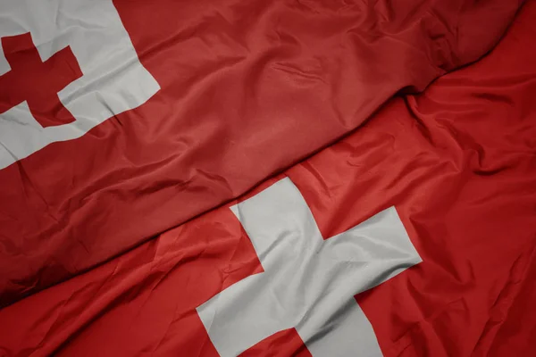 Waving colorful flag of switzerland and national flag of Tonga . — Stock Photo, Image