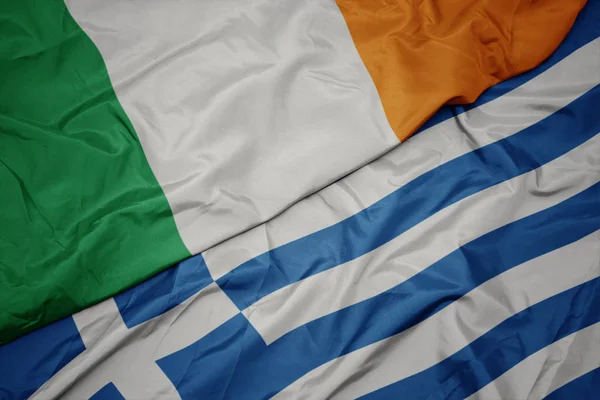 Ondeando colorida bandera de Grecia y bandera nacional de Irlanda . — Foto de Stock