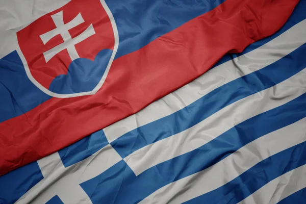 Acenando bandeira colorida da Grécia e bandeira nacional da Eslováquia . — Fotografia de Stock