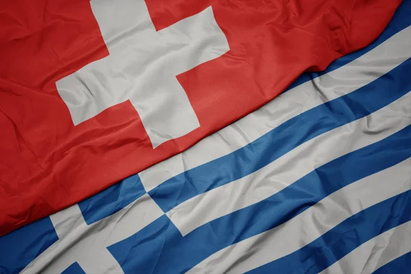 Acenando bandeira colorida da Grécia e bandeira nacional da Suíça . — Fotografia de Stock
